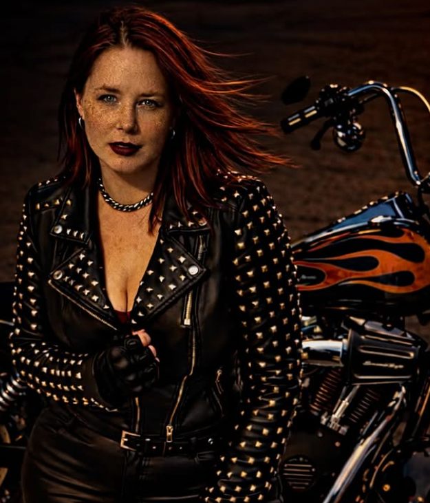 Irian Darkwood in black leather beside a motorcycle